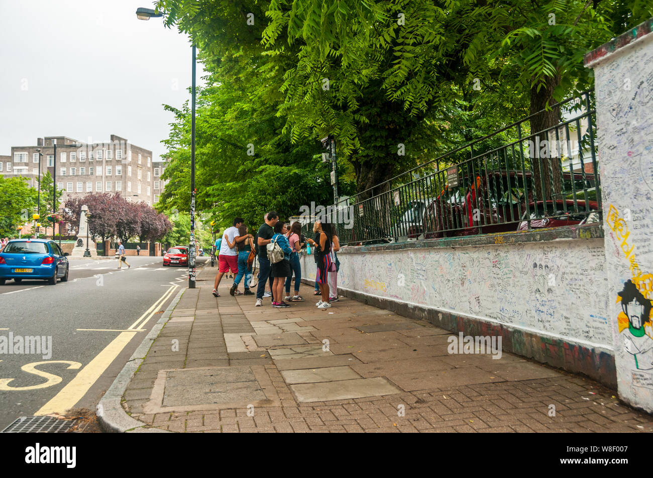 Los turistas con el graffiti en las paredes fuera de los estudios Abbey Road de Londres con el famoso cruce por detrás. Foto de stock