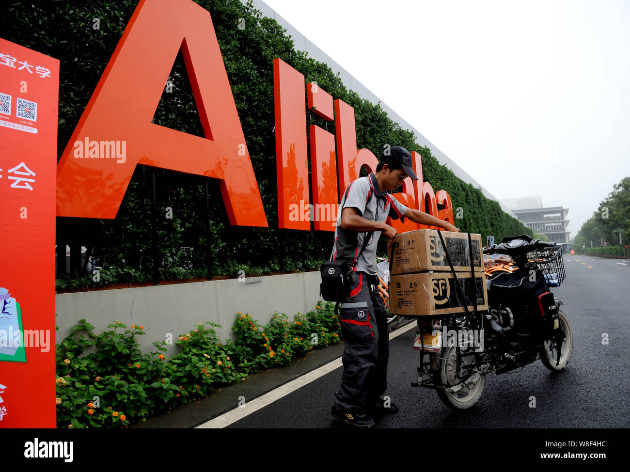 FILE--un chino repartidor de SF Express descarga los paquetes provenientes  de su bicicleta eléctrica delante de una señal de e-commerce gigante chino  Alibaba en Hangzhou Fotografía de stock - Alamy