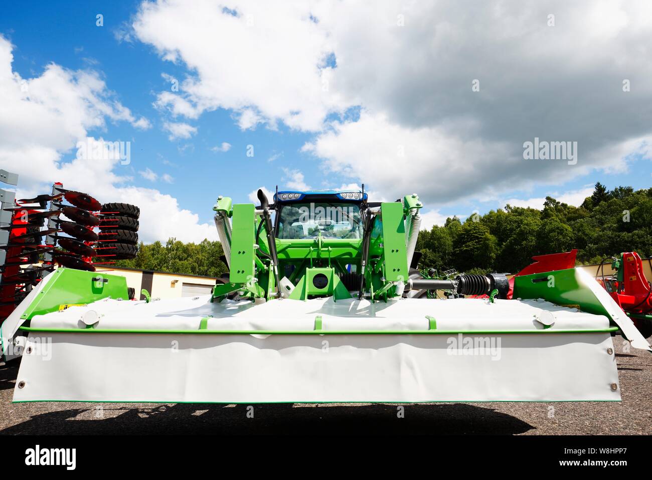 Tractor agrícola con grandes máquinas cortacésped acoplado a la parte frontal con el sistema hidráulico. Foto de stock