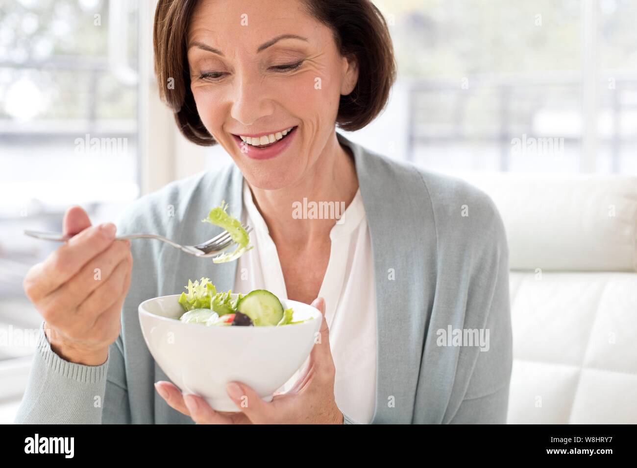Mujer madura comer ensalada. Foto de stock