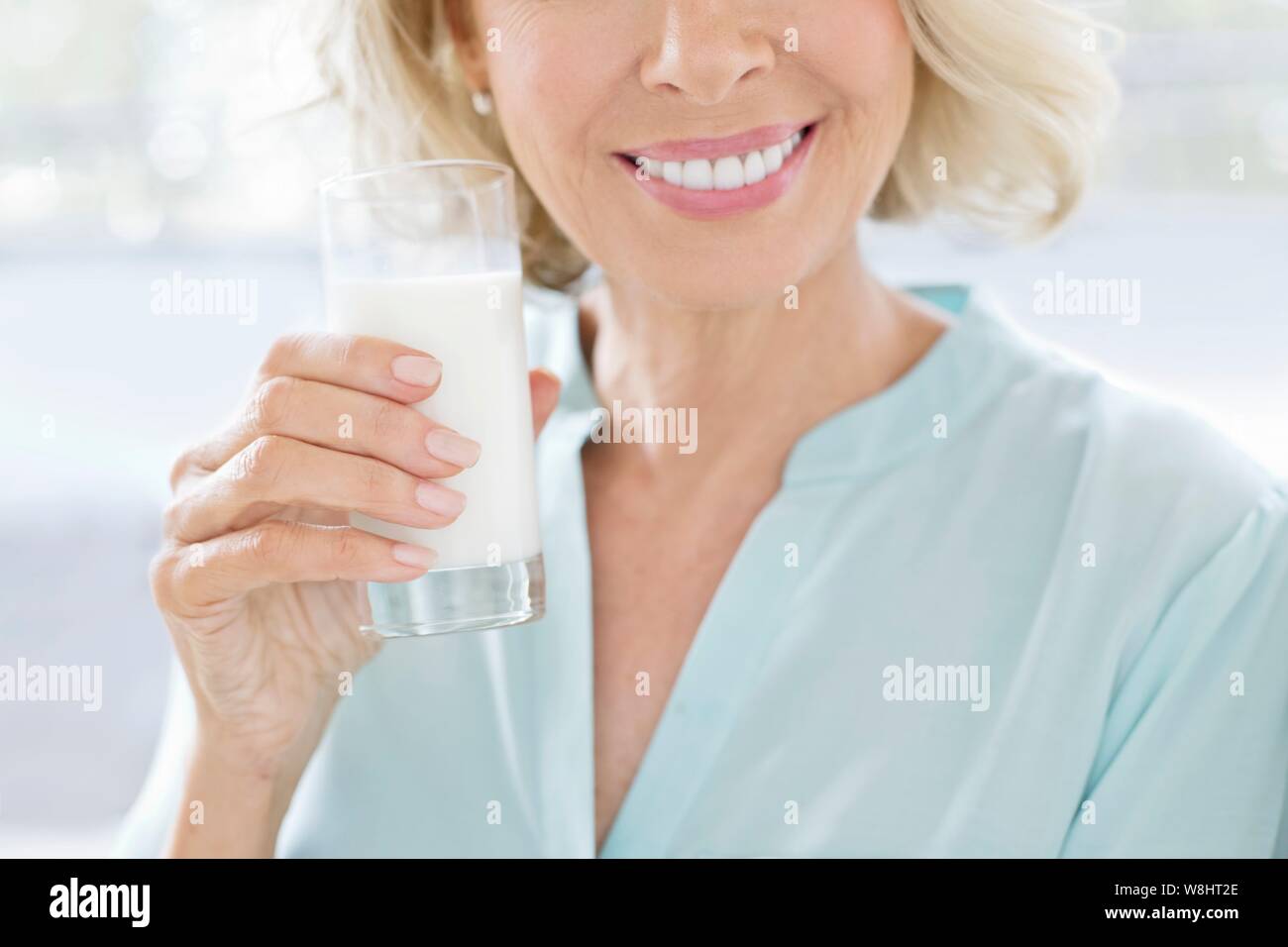Mujer madura sonriente con un vaso de leche. Foto de stock