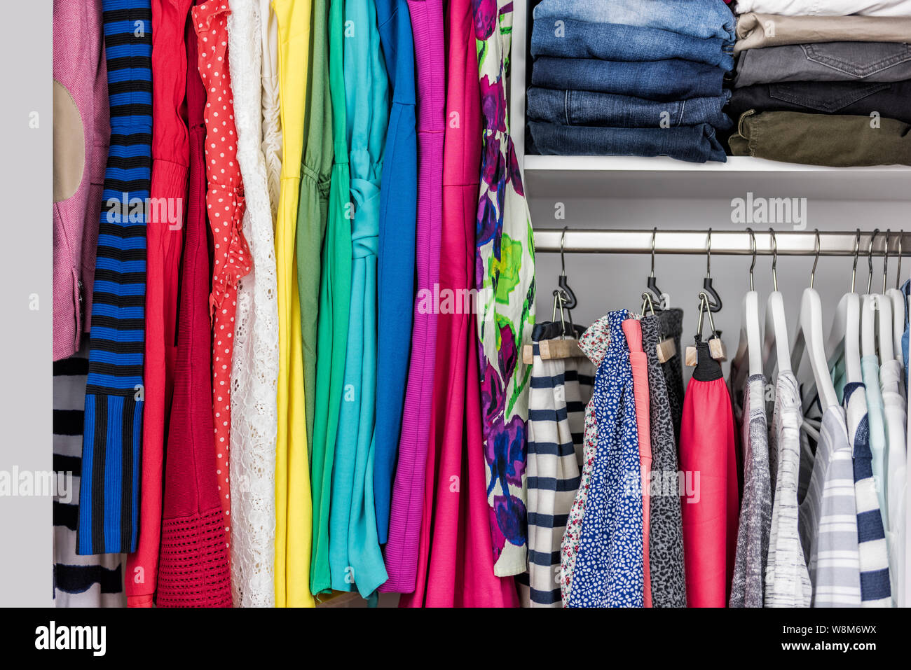 Ropa de moda en walk-in closet de ropa o tienda de compras para mostrar la pantalla. coloridas de trajes de moda bien dispuestos en racks de limpio. Concepto de limpieza de