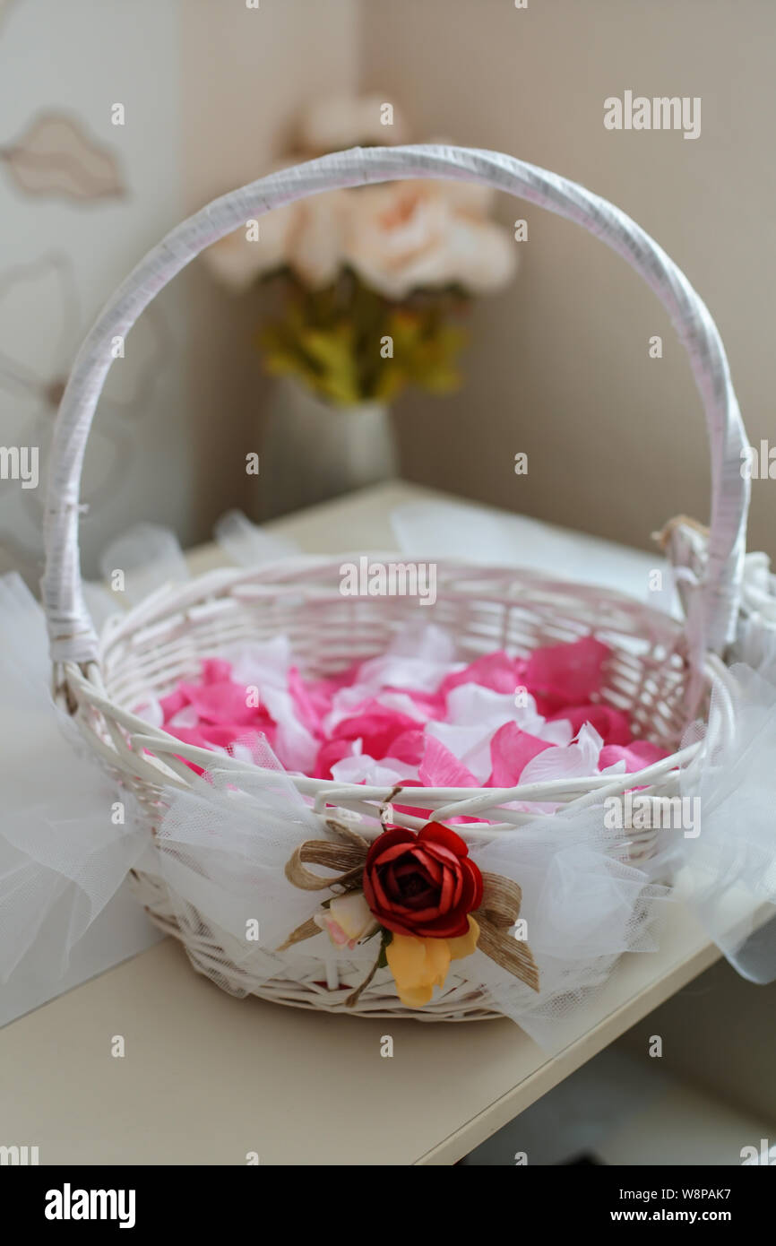 Canasta de paja blanca con pétalos de rosa y accesorios de bodas y otros  regalos en la mesa. Concepto de boda Fotografía de stock - Alamy