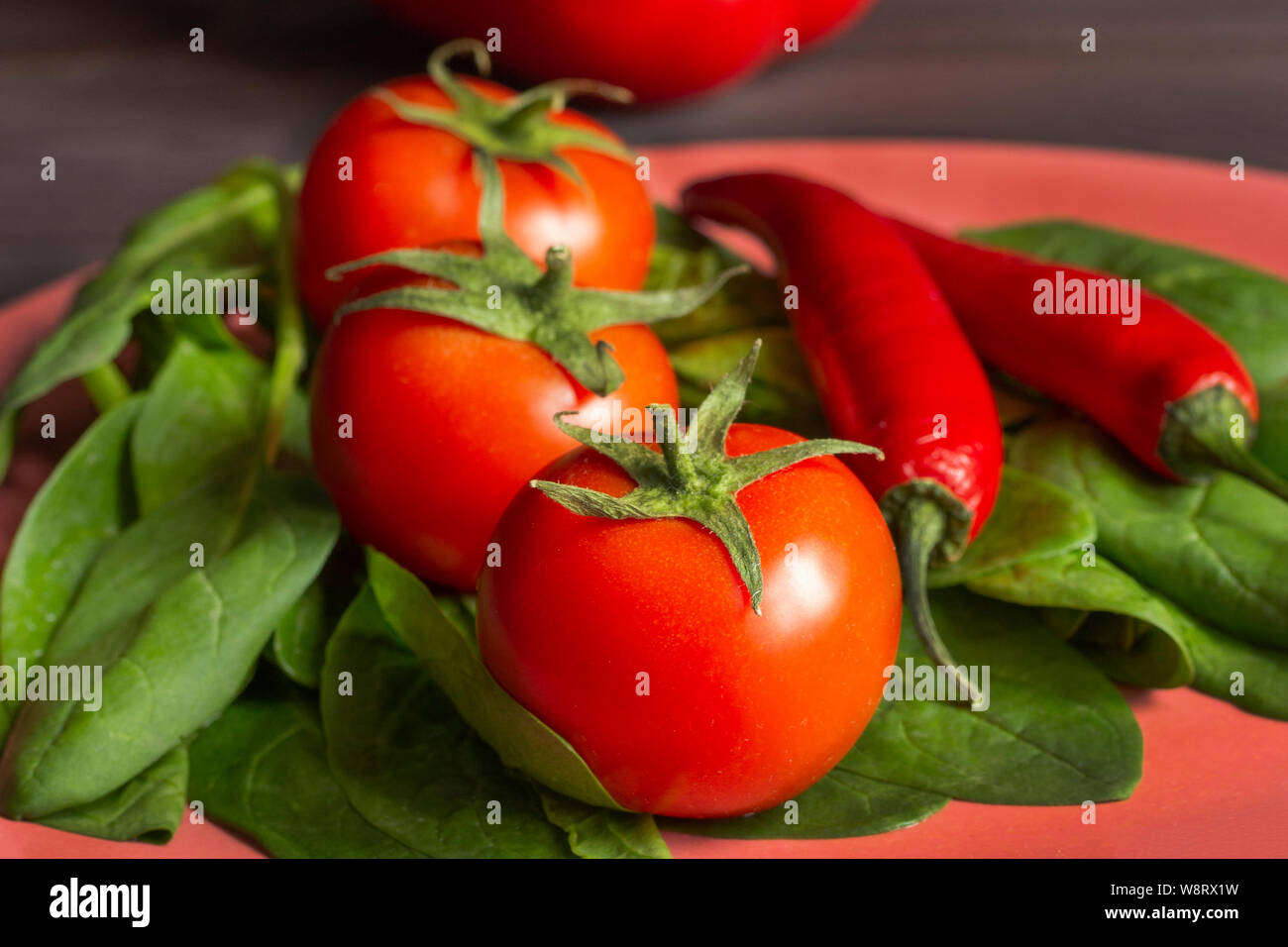 Granja frescos vegetales en una placa de bambú. Tomates espinacas pimientos picantes, vitaminas alimentos orgánicos en cerámica ecológica para los vegetarianos y veganos Foto de stock