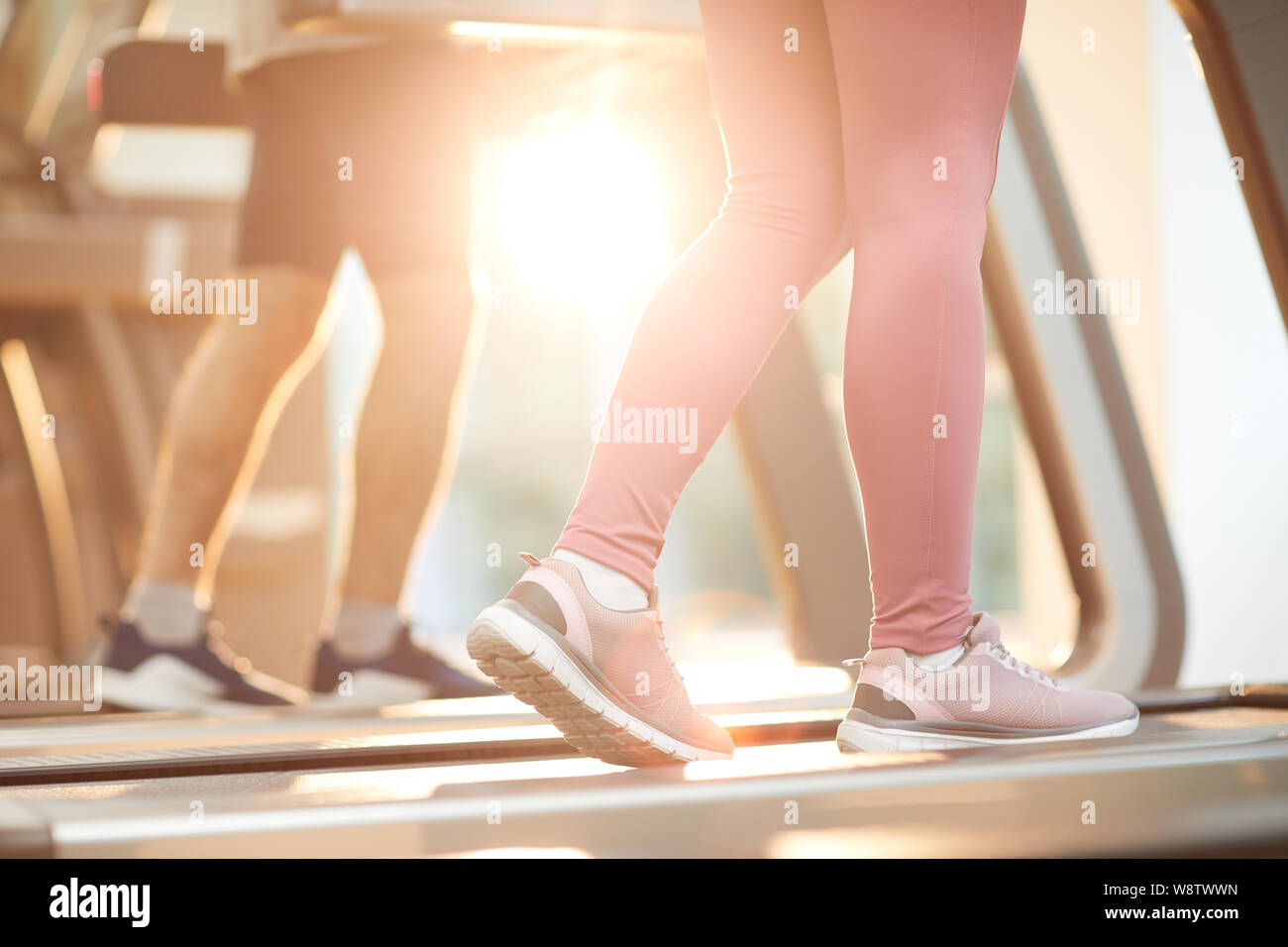 Antecedentes deportivos de personas corriendo en cintas de correr en el gimnasio iluminado por la luz solar, espacio de copia Foto de stock
