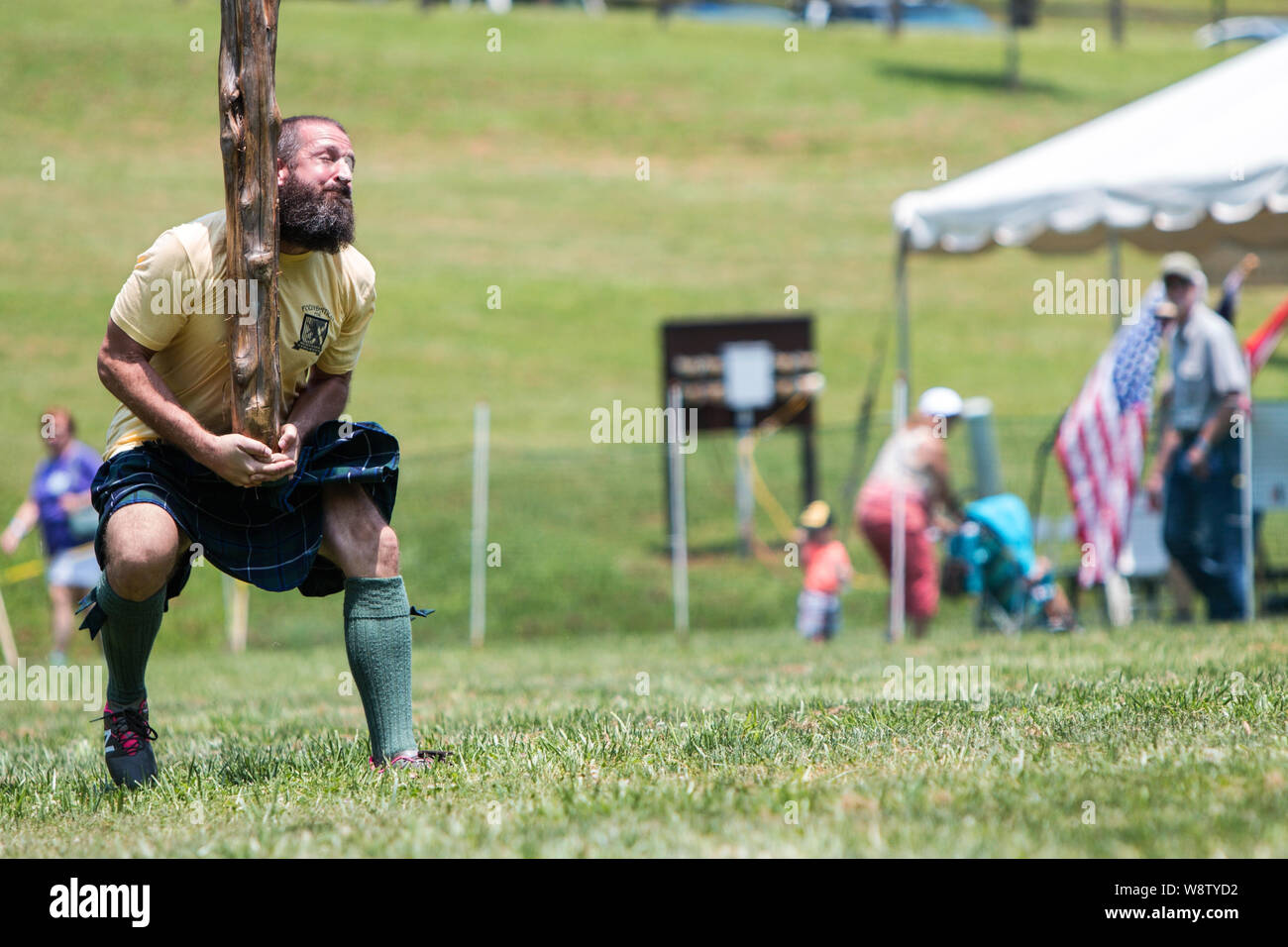 Un hombre corre en posición para realizar una caber toss, arrojando un registro cónico, a Blairsville Scottish Highland Games en Blairsville, GA. Foto de stock