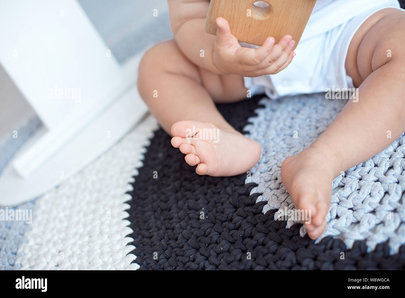 Bebé de 4 meses de edad sentado con los pies descalzos sobre una alfombra.  Juguetes en primer plano Fotografía de stock - Alamy