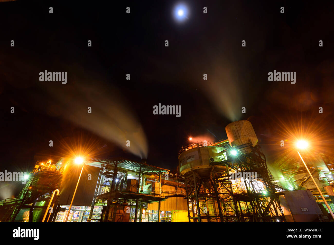El molino de azúcar de Mulgrave con fumar chimeneas de aplastamiento, mientras que la caña de azúcar en la noche, operado por MSF, Gordonvale, Far North Queensland, FNQ, QLD, Australi Foto de stock