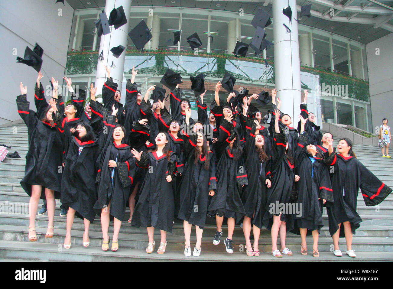 Archivo-chino vestidas en trajes de bachillerato lanzan sombreros al aire durante una ceremonia de graduación en la Universidad de Zhejiang A&F Hang Fotografía de stock -