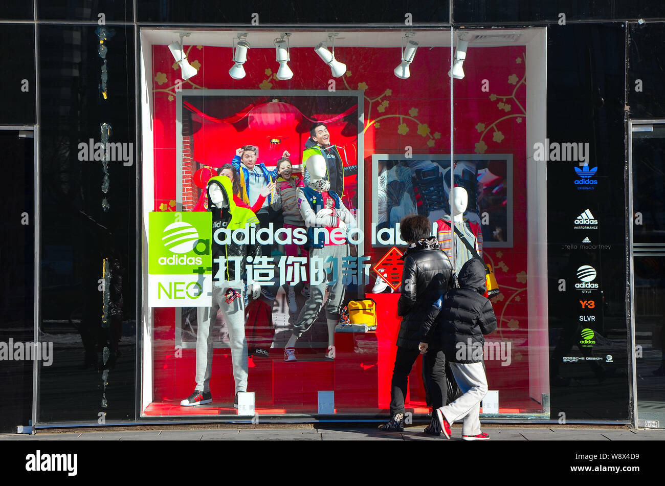 FILE--peatones mirar en el escaparate de una tienda de ropa deportiva de  Adidas en Sanlitun Village, Beijing, China, 4 de febrero de 2013. La  primera Adidas nueva Fotografía de stock - Alamy