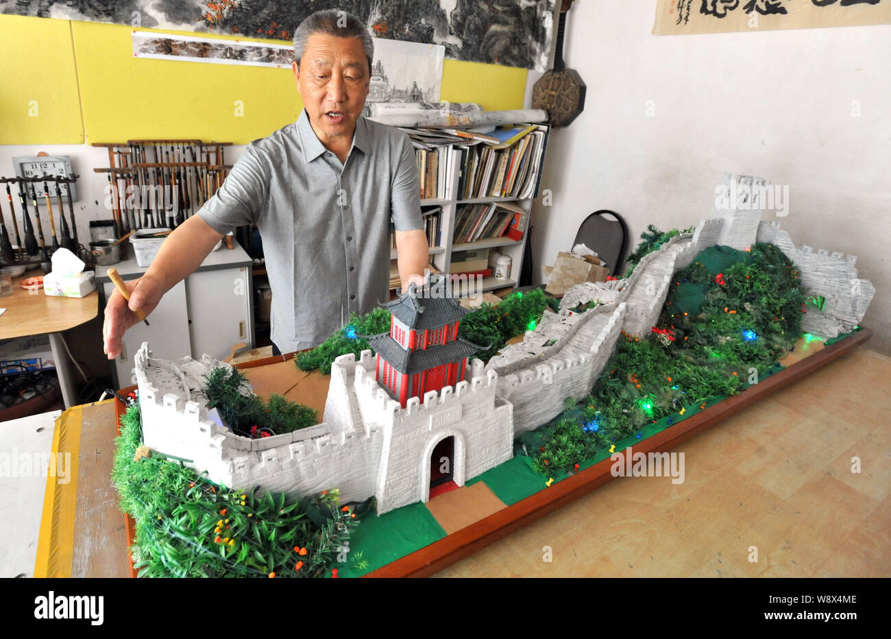 68-año-viejo jubilado chino Desheng habla como él el toque final de su miniatura caseros de una sección de la Muralla de Qi en Qingdao cit Fotografía de stock -