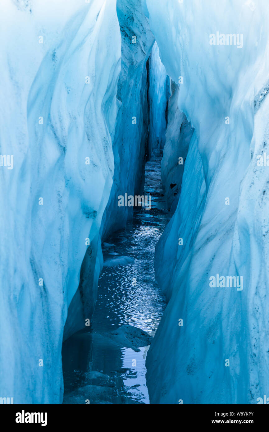 Paredes encorvadas dentro de un glaciar alpino crevasse en Alaska. Dentro de una profunda grieta llena de agua. Foto de stock