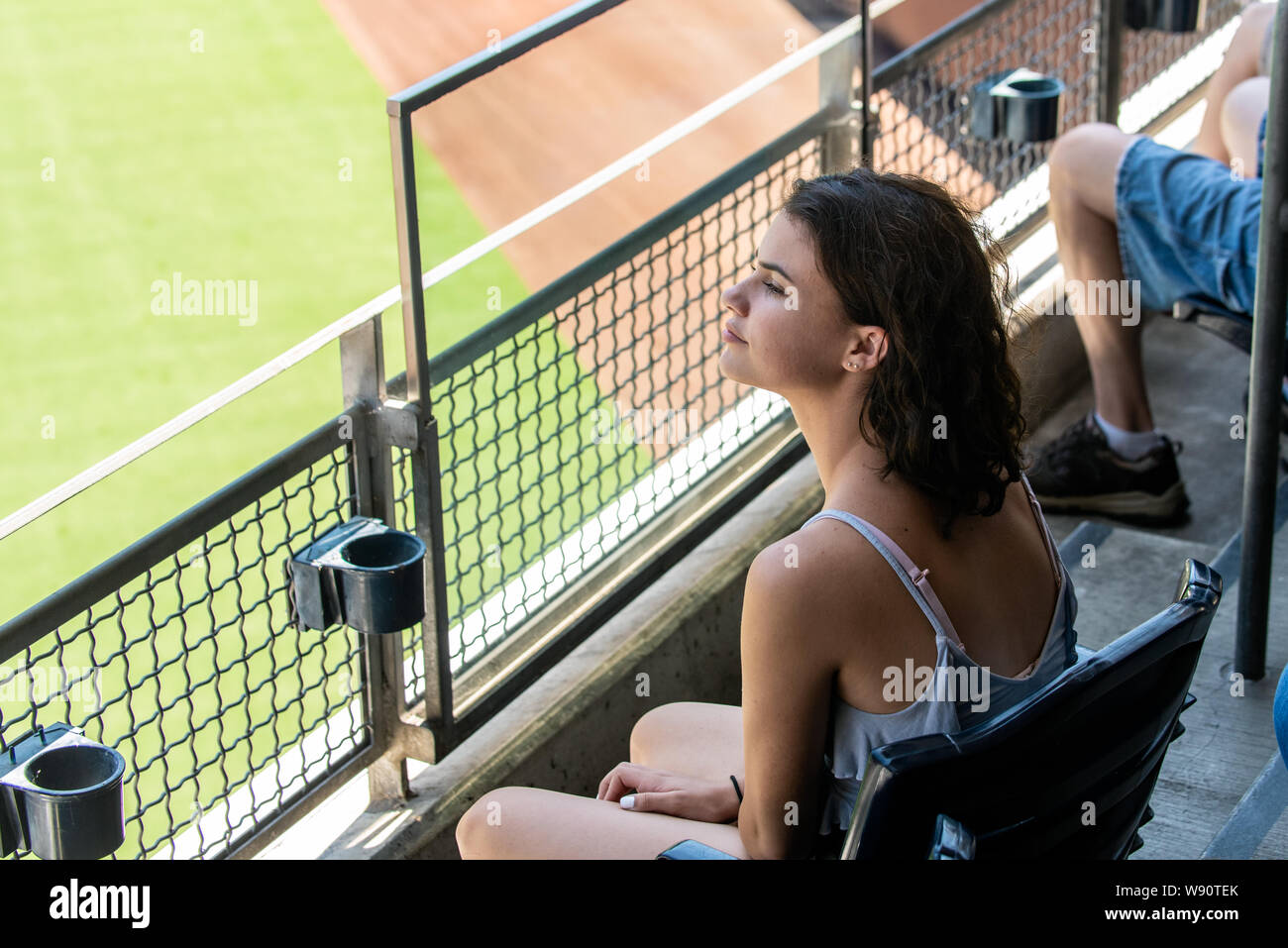 Adolescente femenino aficionado sentado en primera fila del piso superior para una perfecta visualización en lugar del estadio. Foto de stock