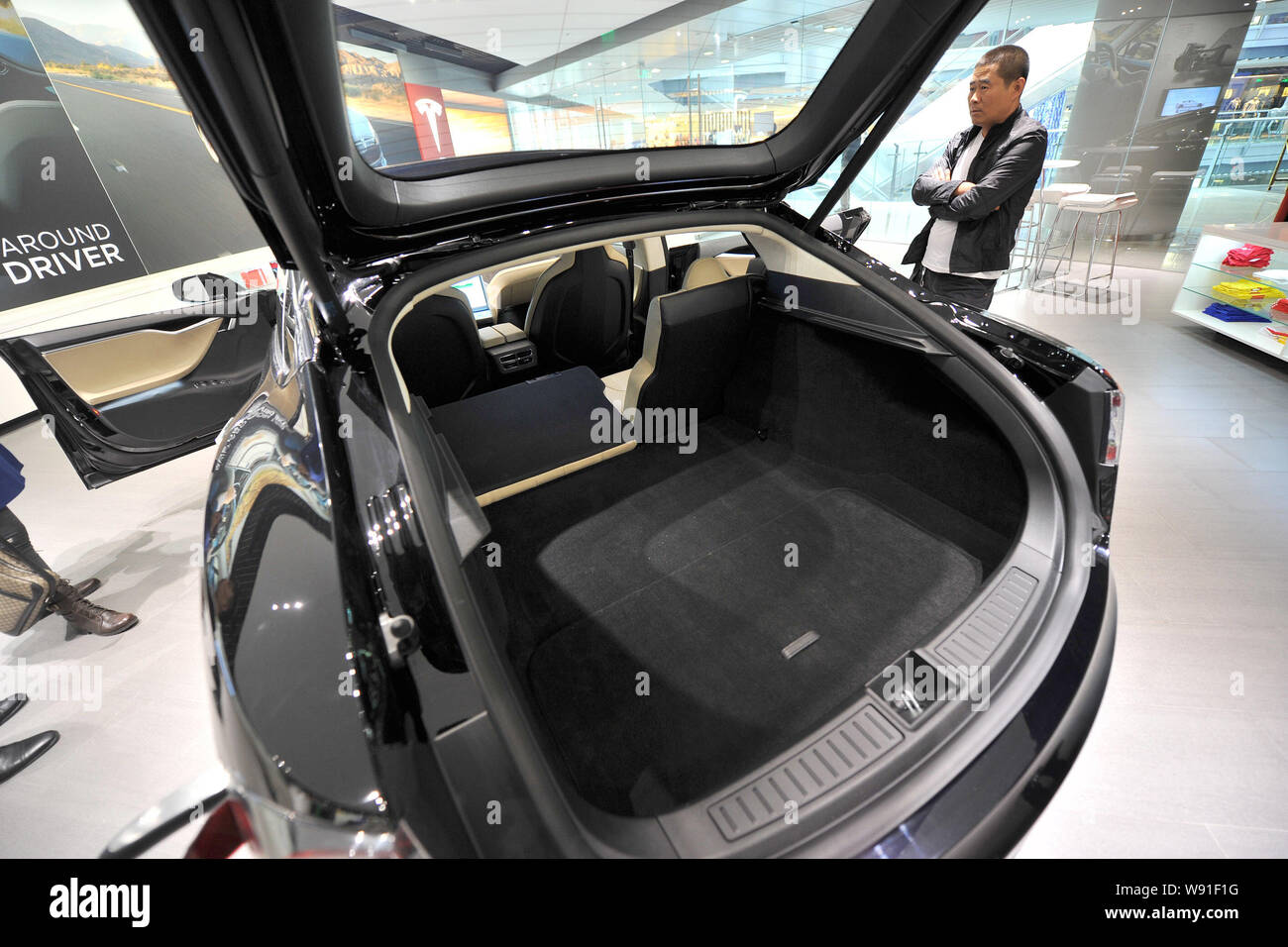 Los visitantes miran un modelo negro S coche eléctrico en exhibición en la tienda Tesla en Beijing, China, 5 de noviembre de 2013. Nosotros fabricante de automóviles eléctricos Tesla Motors op Foto de stock