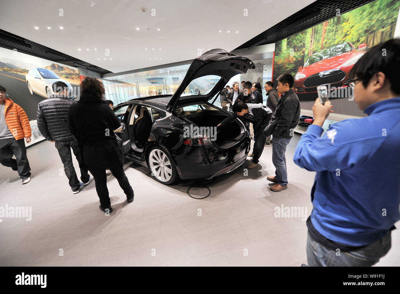Los visitantes miran un modelo negro S coche eléctrico en exhibición en la tienda Tesla en Beijing, China, 5 de noviembre de 2013. Nosotros fabricante de automóviles eléctricos Tesla Motors op Foto de stock