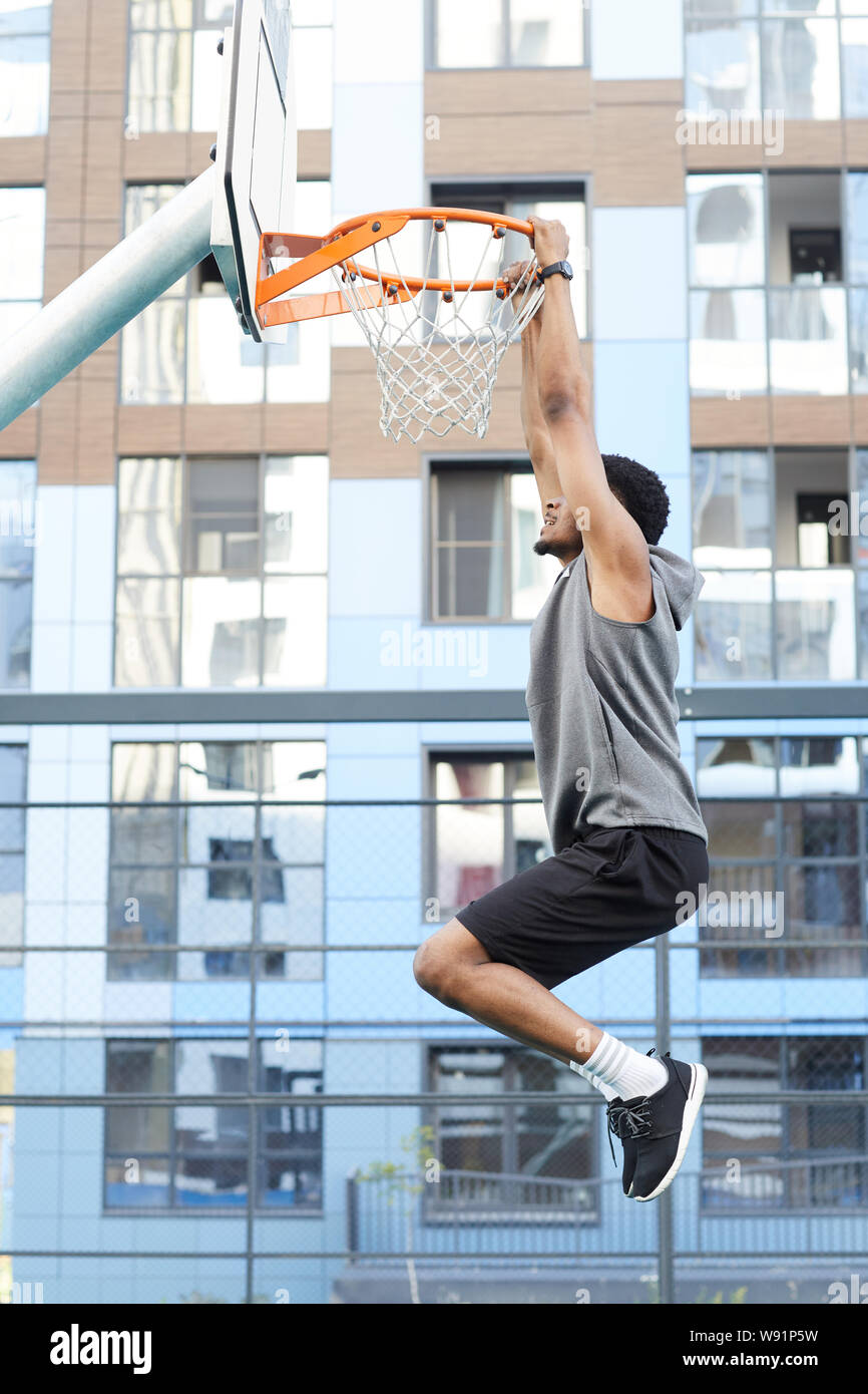 Vista lateral de disparo de acción del jugador de baloncesto africano saltando al aro, mientras que la capacitación en corte, copie el espacio exterior Foto de stock