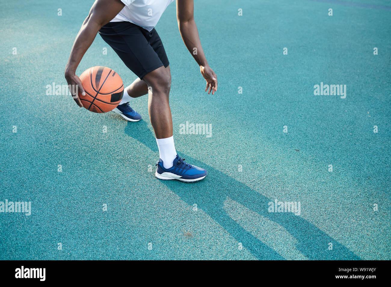 Acción de ángulo bajo foto de hombre afroamericano jugando baloncesto al aire libre, espacio de copia Foto de stock