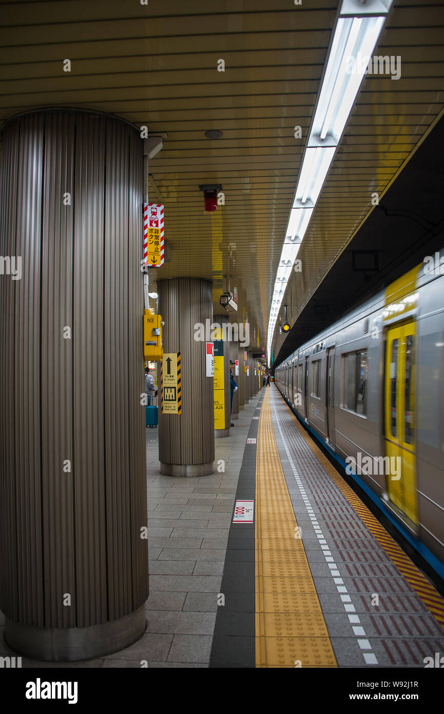 Tokio, Japón - Abril 2019: un tren subterráneo en movimiento a lo largo de una plataforma bien iluminado en una estación de metro japonés. Foto de stock