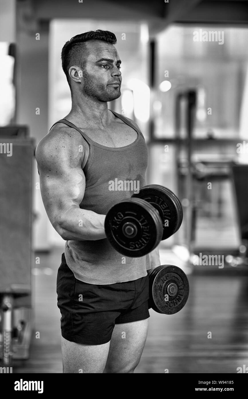 Un hombre guapo está ejercitando el pecho con barra en un gimnasio moderno