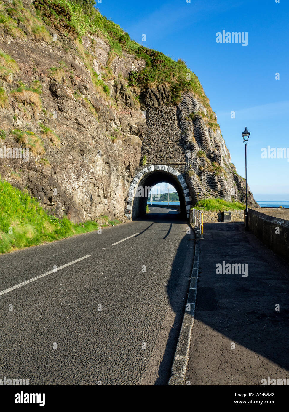 Arco negro túnel y Causeway Ruta Costera. Carretera Escénica a lo largo de la costa oriental del Condado de Antrim, Irlanda del Norte, Reino Unido. Vista aérea de la luz del amanecer Foto de stock