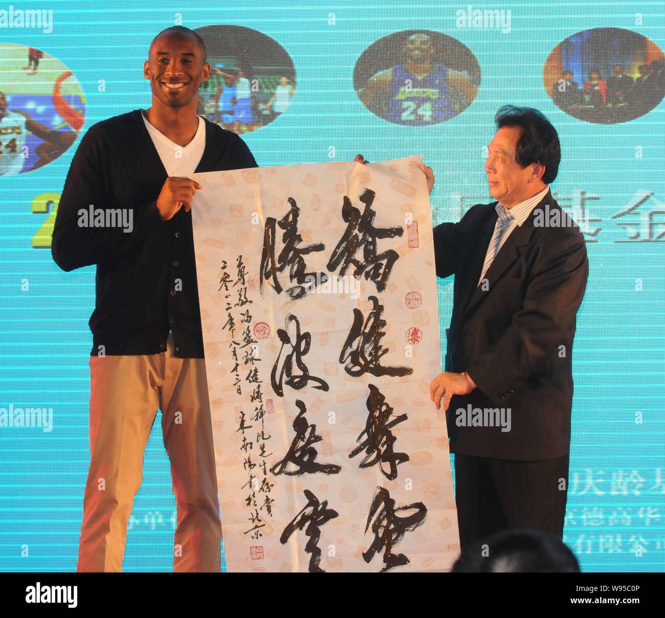 La estrella de la NBA KOBE Byrant, izquierda, recibe un trabajo caligráfico como regalo de un invitado durante un banquete de caridad de la Kobe Bryant en Shanghai, China Fund Foto de stock