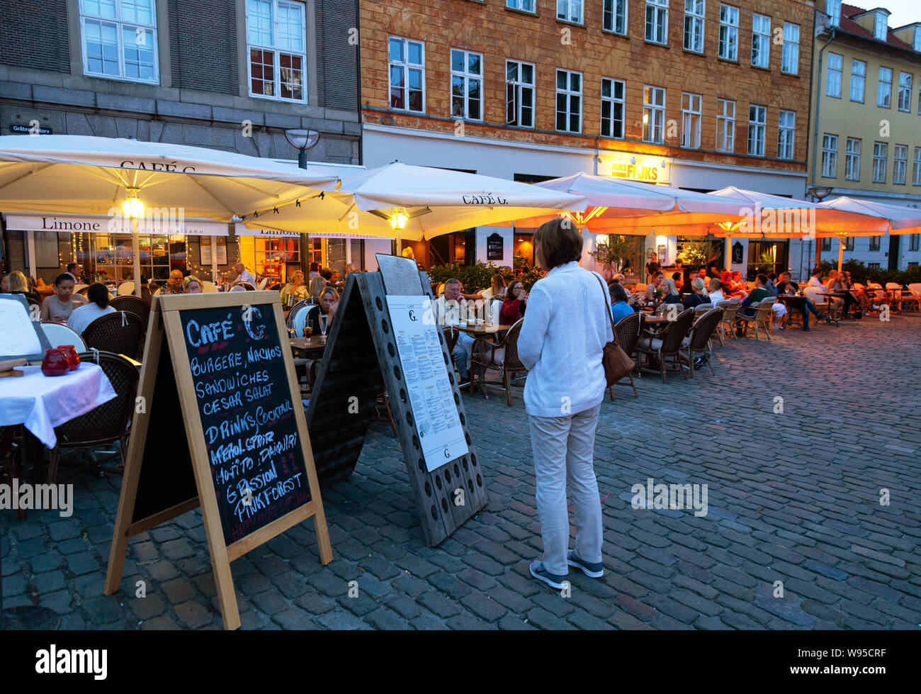 Restaurante de Copenhague; una mujer mirando el menú, en una noche de verano, cafetería, restaurante, Gråbrødretorv G, el Barrio Latino, Copenhague, Dinamarca Escandinavia Foto de stock