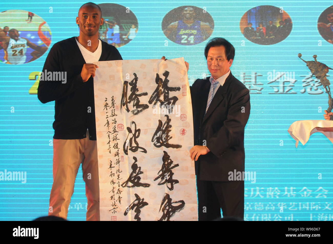 La estrella de la NBA KOBE Byrant, izquierda, recibe un trabajo caligráfico como regalo de un invitado durante un banquete de caridad de la Kobe Bryant en Shanghai, China Fund Foto de stock