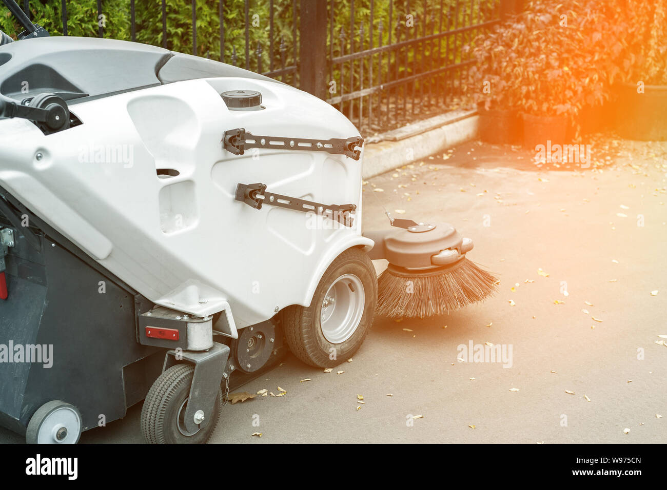 Pequeña Máquina barredora en el estacionamiento permanente de  almacenamiento después de la limpieza del parque de la ciudad alley.barrer  vehículo aspirador para quitar el polvo y las hojas caídas en Fotografía de