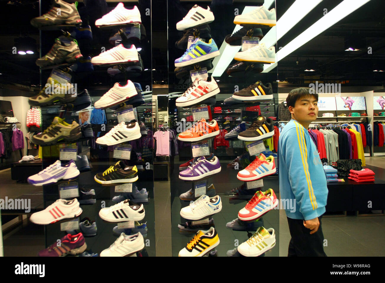 Un personal Chino se erige junto a adidas zapatos deportivos en exhibición  en una tienda de ropa deportiva de Adidas en Shanghai, China, 23 de febrero  de 2011. Adidas AG registró r