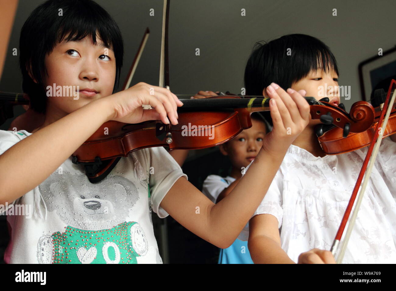 Los niños aprenden a tocar el violín chino en la ciudad, Distrito de Pinggu  Donggaocun, Beijing, China, 12 de agosto de 2010. Las estadísticas muestran  que un tercio de los mundos vio
