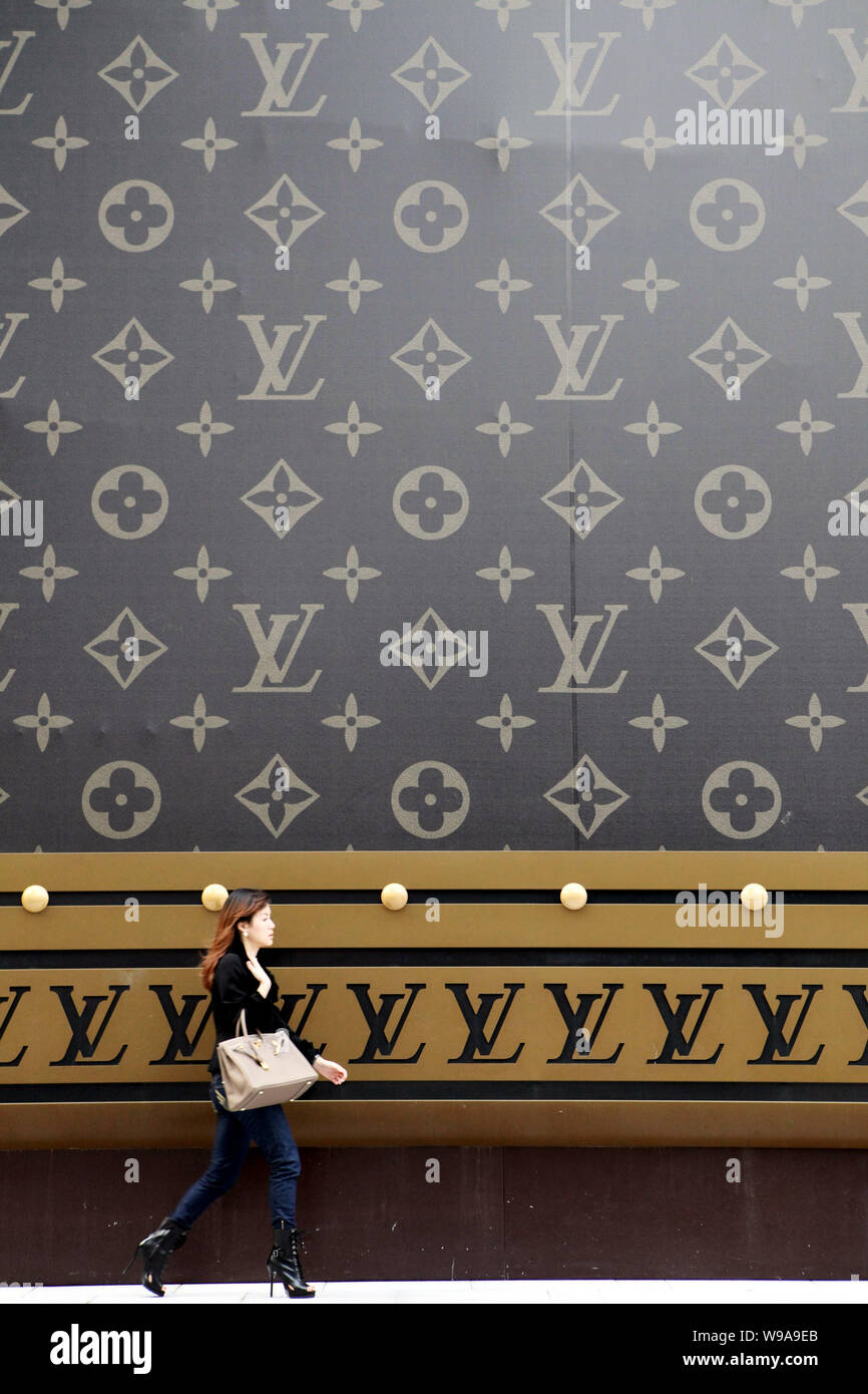 Una atractiva mujer que llevaba un Hermes Birkin handbag camina delante de  una enorme Louis Vuitton (LV) maleta fuera del centro comercial Plaza 66 en  Shanghai, China, 4 Fotografía de stock - Alamy