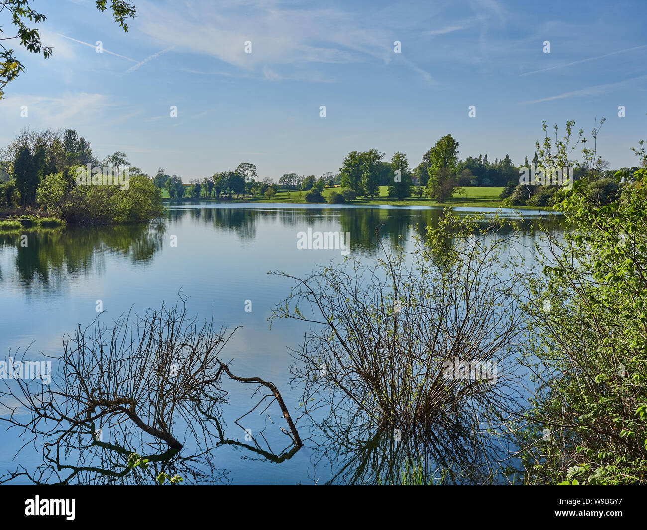 Lago Culverthorpe en Lincolnshire en una tranquila jornada soleada de primavera con reflexiones sobre el agua Foto de stock