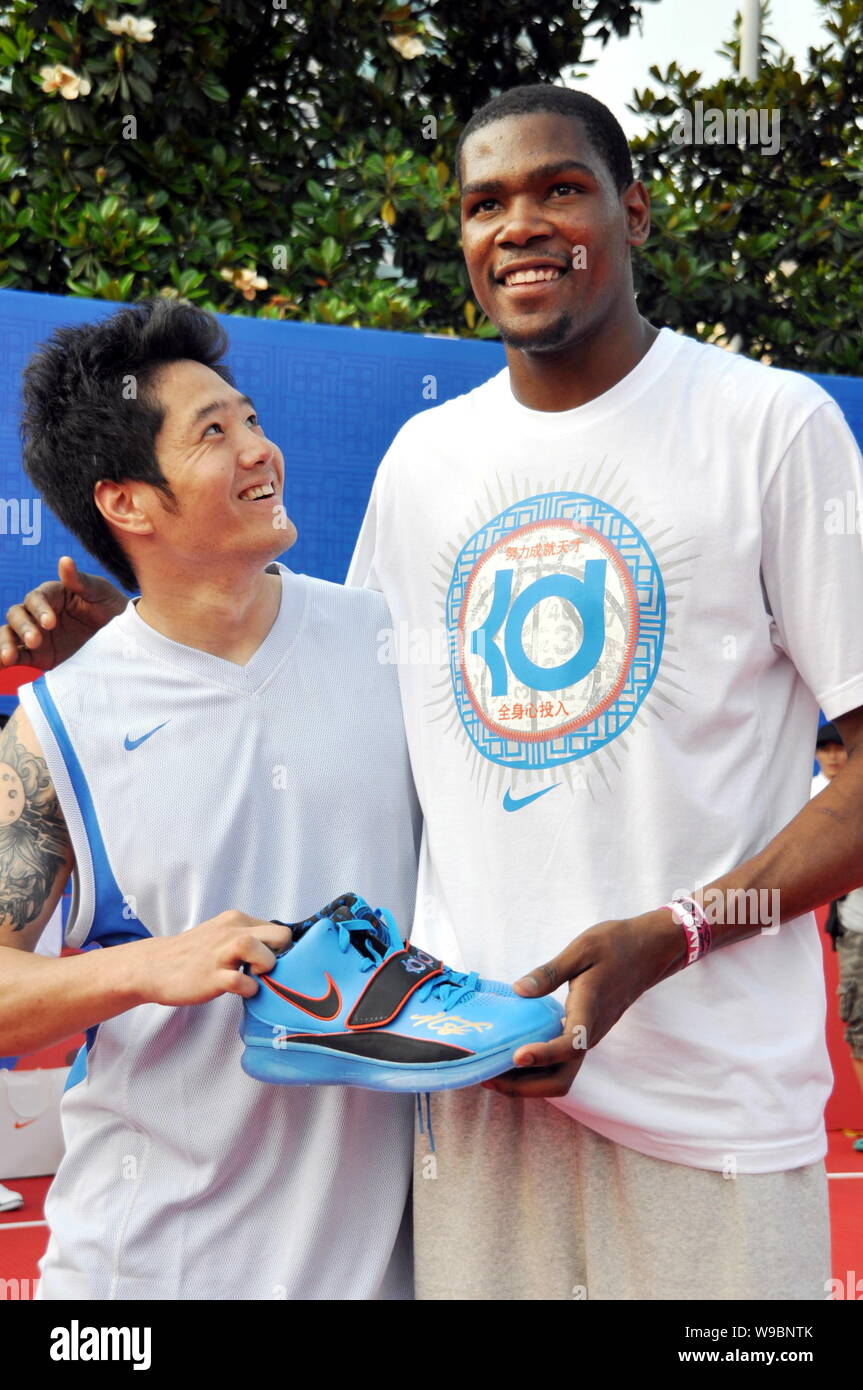 El jugador de la NBA, Kevin Durant, derecho Oklahoma City presenta un par de zapatillas con su firma a un abanico chino durante un campamento de entrenamiento en baloncesto Fotografía de
