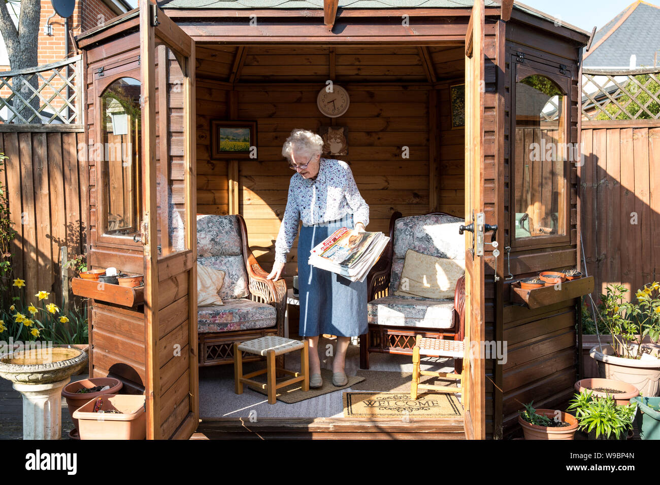 Mujer mayor fuera en su jardín de verano en una casa residencial, suroeste de Inglaterra, Reino Unido Foto de stock