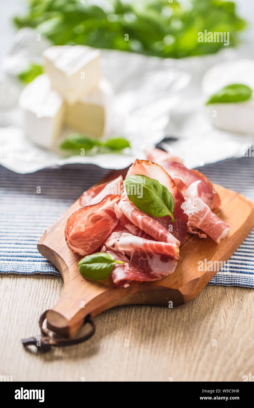 Jamón de cerdo jamón y queso brie o camembert con las hojas de albahaca sobre la mesa Foto de stock