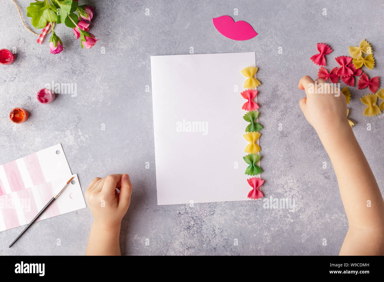 Manualidades con papel para el día de la madre, el 8 de marzo o el  cumpleaños. Niño pequeño haciendo un ramo de flores de papel coloreado y  pasta de color Fotografía de