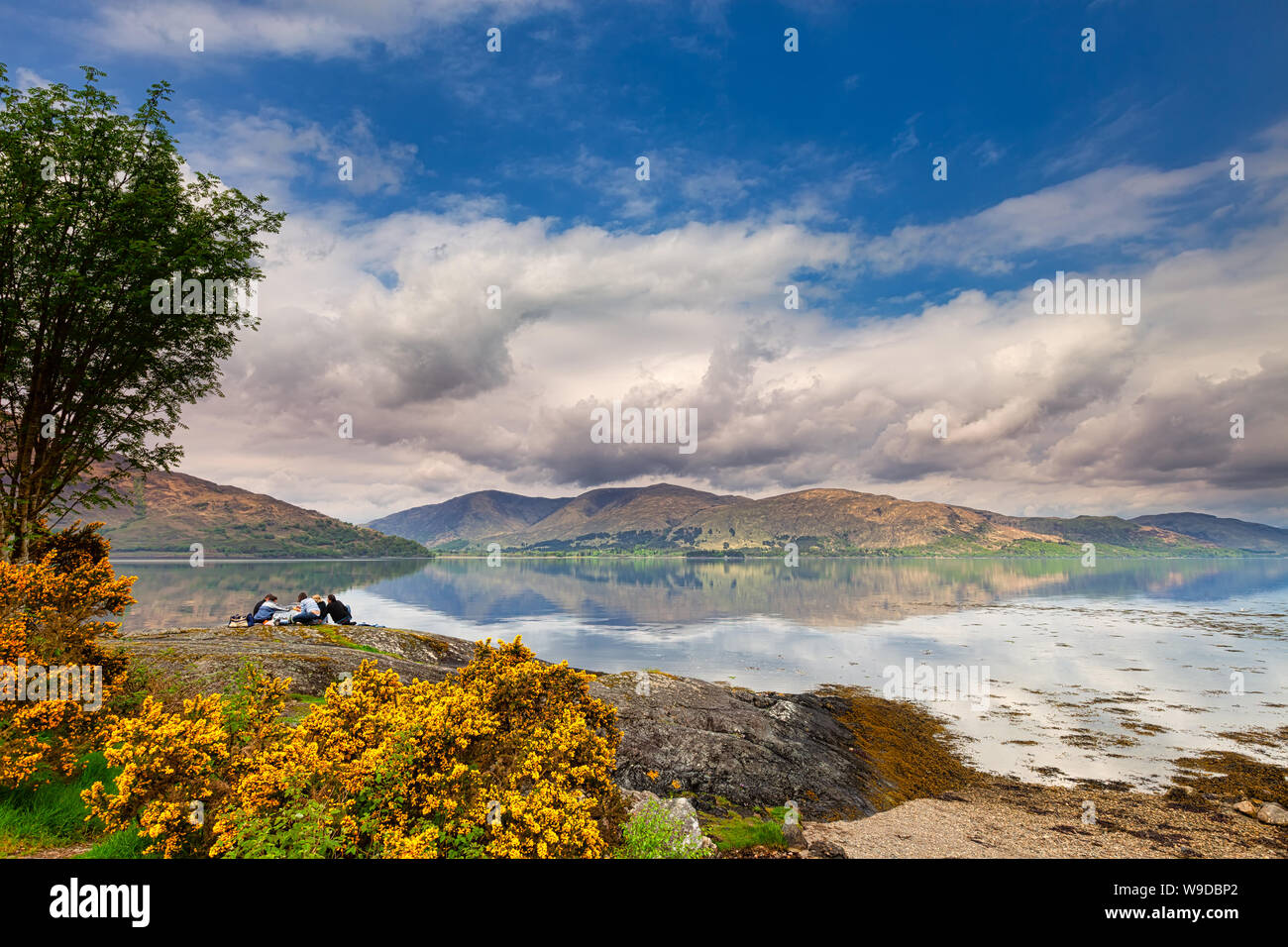 La gente tener un picnic relajante en el Loch Linnhe en las tierras altas en un día de primavera - costa oeste de Escocia - imagen de viajes Foto de stock