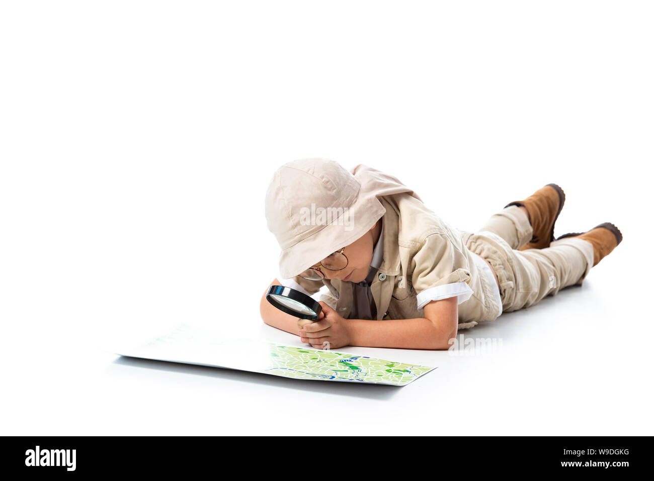 Centrado en el niño explorador sombrero y gafas mirando el mapa a través de  la lupa sobre blanco Fotografía de stock - Alamy