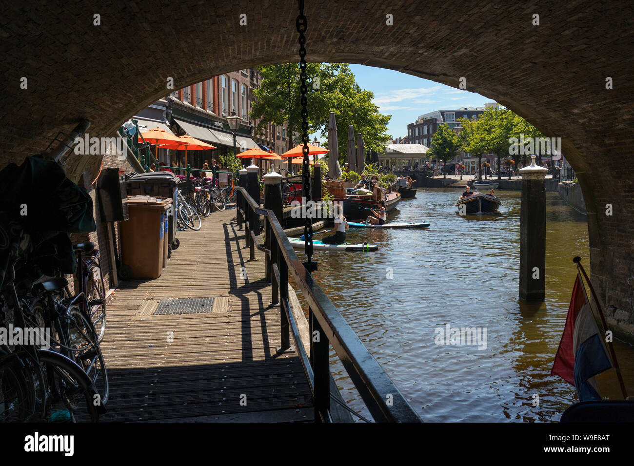 Leiden, Holanda - Julio 05, 2019: el corredor, de camino a pie bajo el puente sobre el Nieuwe Rijn canal Foto de stock