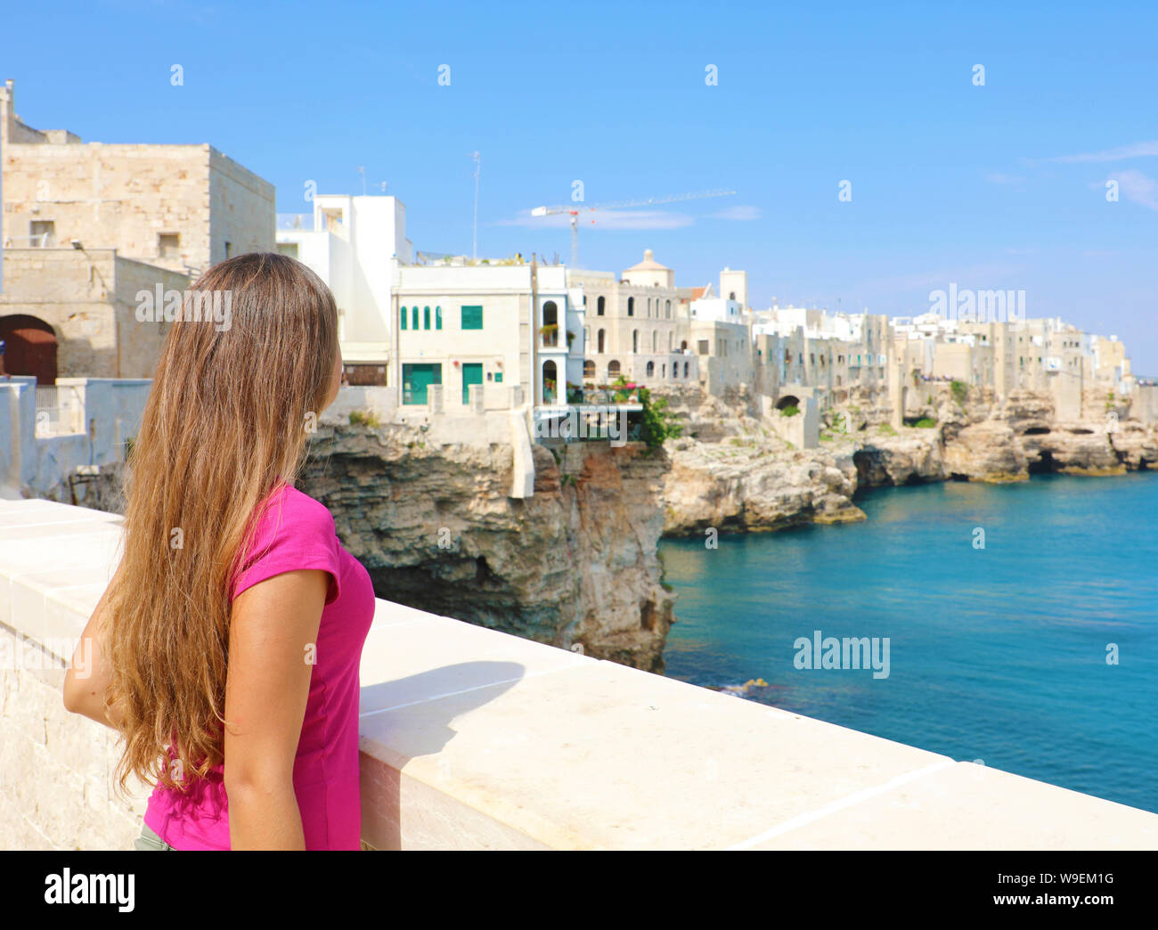 Vista posterior de la hermosa joven en Polignano a Mare town en el Mar Mediterráneo, Italia. Foto de stock