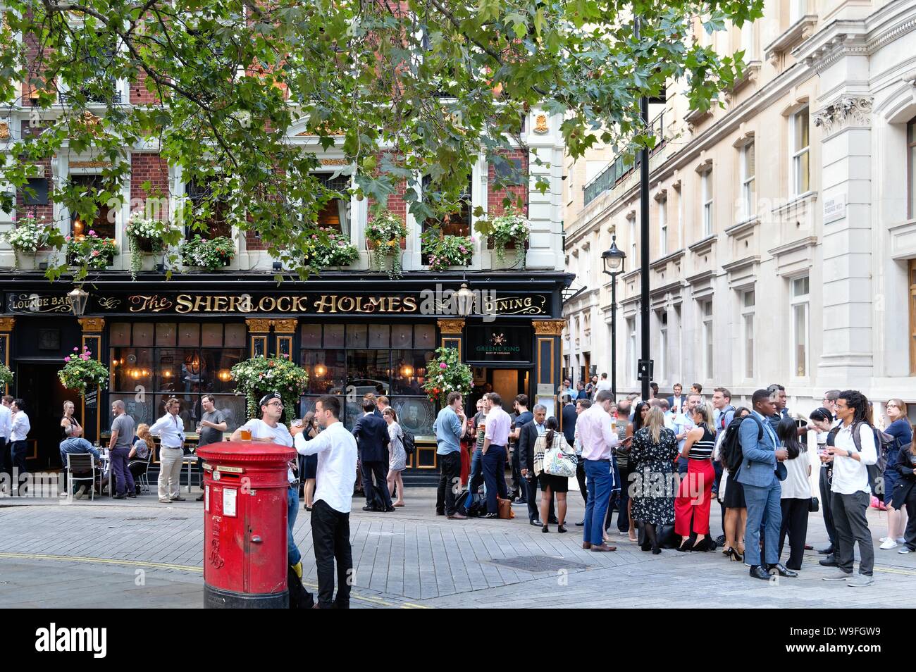 Las multitudes disfrutando de una copa de noche de verano fuera de la casa pública de Sherlock Holmes en Northumberland Street, en el centro de Londres, Inglaterra Foto de stock