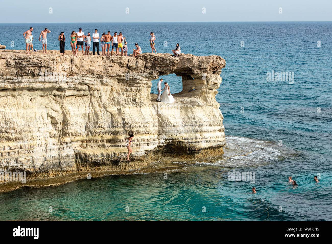 La gente de pie y sentada sobre las rocas, disfrutando de las aguas cristalinas y una joven pareja de casados obtener la fotografía Foto de stock