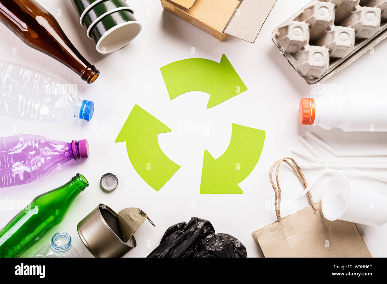 Vista superior de diferentes materiales con símbolo de reciclado de basura  en el fondo de la tabla de madera blanca. Día Mundial del Medio Ambiente,  reciclaje y concepto Eco Fotografía de stock -