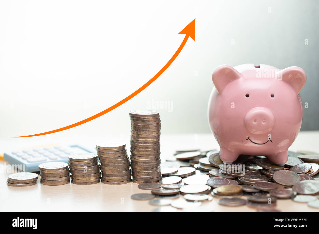 Ahorro de dinero concepto.business ricos ingresos muestran como pila dinero coin creciente con flecha hucha sonrisa con monedas montón. Foto de stock