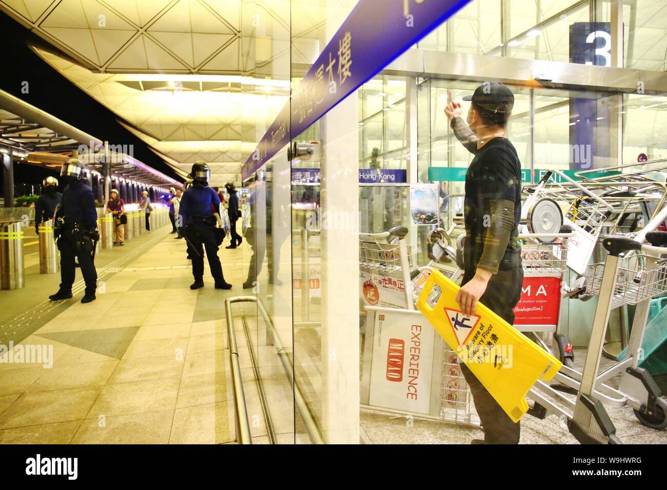 Hong Kong. 13 Aug, 2019. Los disturbios estallan en el Aeropuerto Internacional de Hong Kong, cuando la policía intentan rescatar a dos hombres chinos que son sospechosos de ser agentes encubiertos de la China continental y, por tanto, retenidos por los manifestantes en el interior del aeropuerto. Los enfrentamientos estallan a media noche, spray de pimienta se usa y unos pocos manifestantes son arrestados. Crédito: Gonzales Foto/Alamy Live News Foto de stock