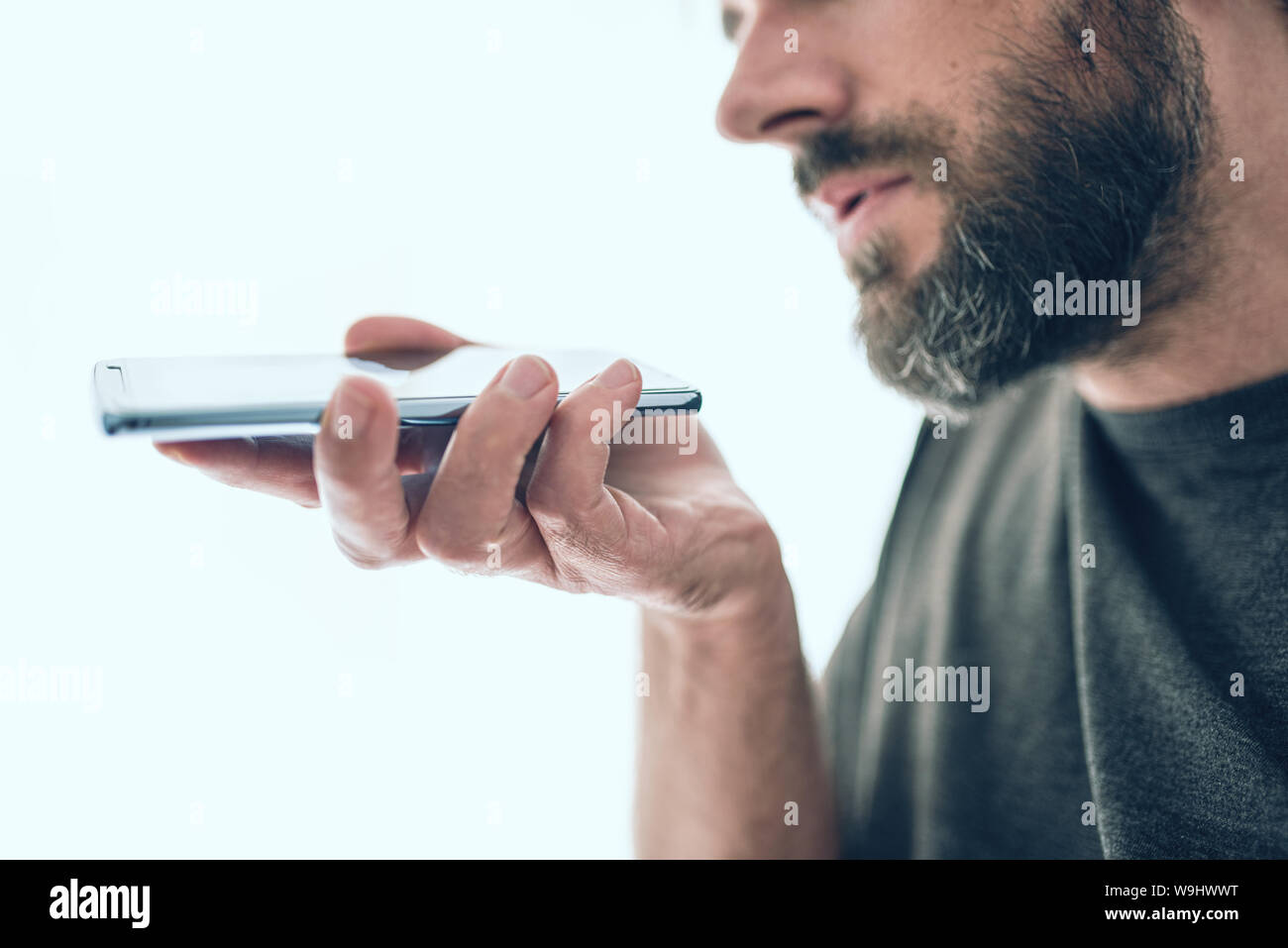 Close-up de barbudo hombre caucásico la grabación de mensajes de voz o mediante voz assistant en teléfono móvil Foto de stock