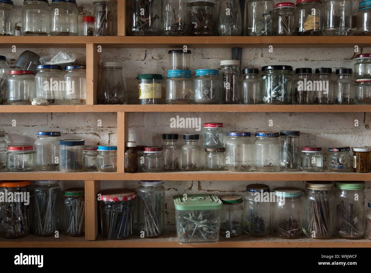 Filas de tarros de vidrio reciclado de envases utilizados para almacenar  diferentes tamaños de tornillos, clavos, barcos, arandelas, tuercas de  manera organizada Fotografía de stock - Alamy