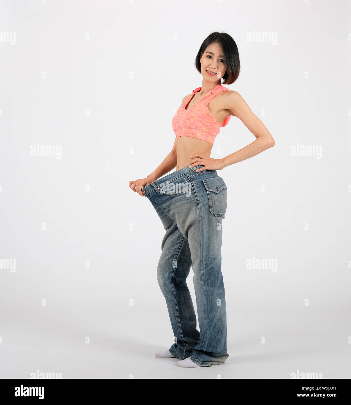 Gimnasio deportivo mujer en vaqueros después de perder peso sobre fondo deporte saludable estilo de vida Fotografía de stock - Alamy