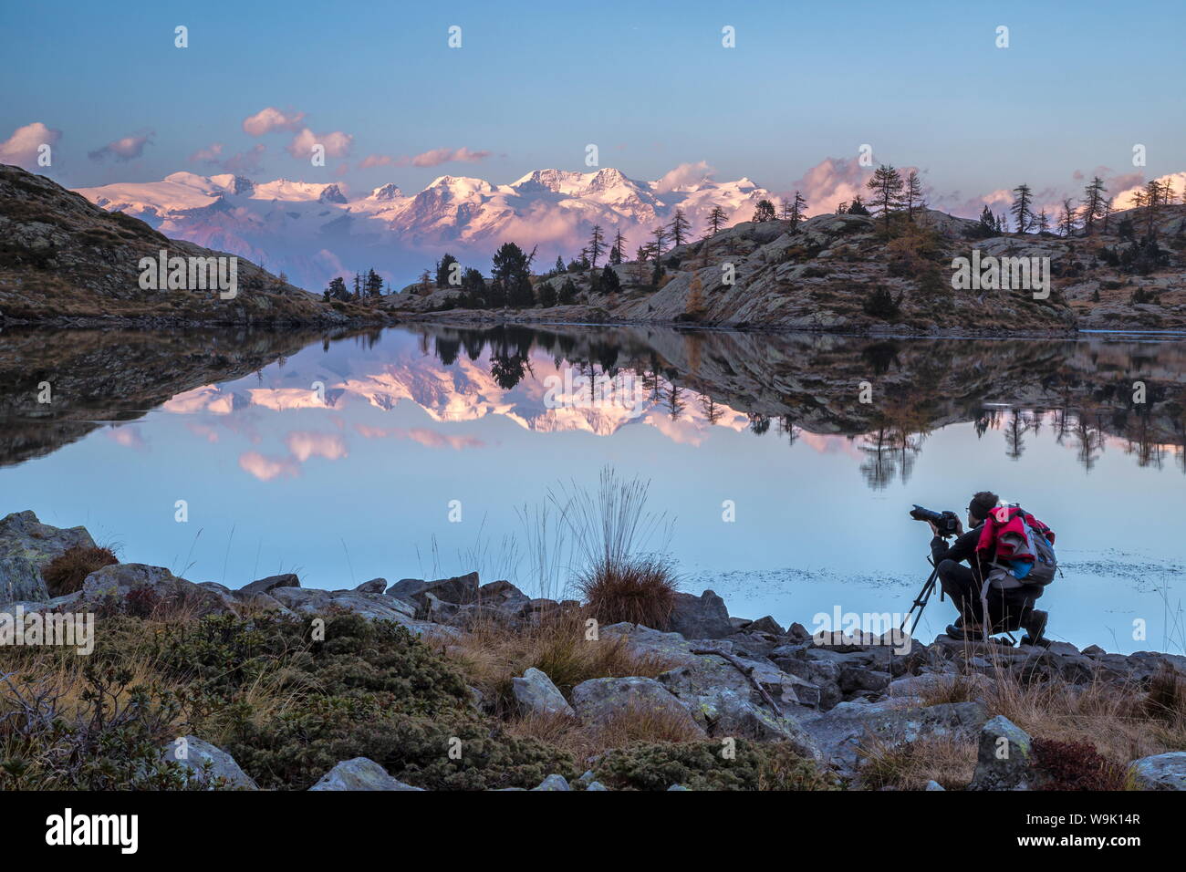 Un fotógrafo contemplando la puesta de sol sobre el Monte Rosa del Lago Bianco, en el Parque Natural del Mont Avic, Valle de Aosta, Italia, Europa Foto de stock