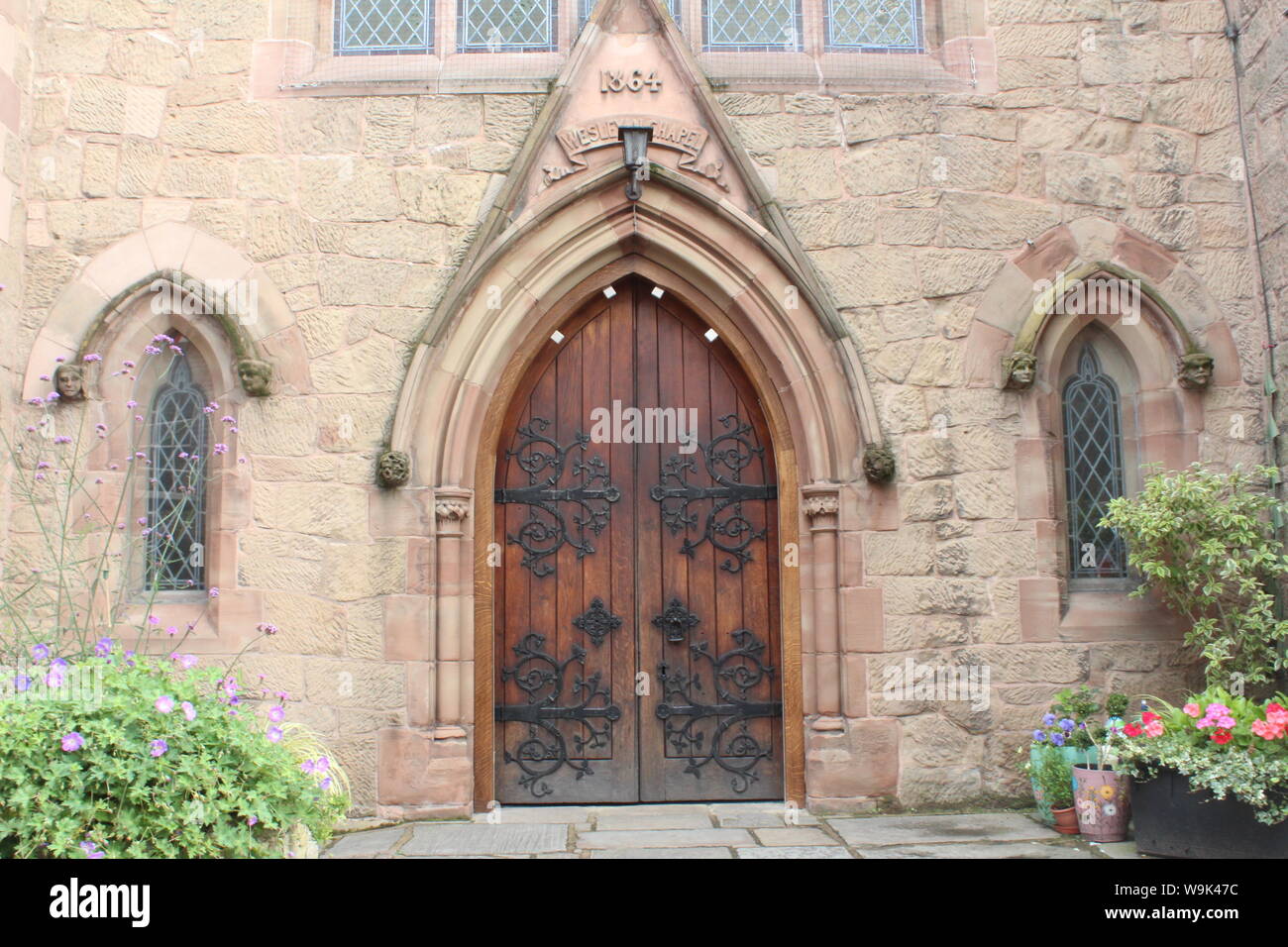 Imagen de la puerta bellamente diseñados de la iglesia metodista de Knutsford con pequeñas plantas y flores delante de él. Foto de stock